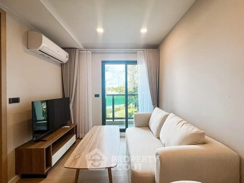 Modern living room with cozy sofa, flat-screen TV, and large window offering natural light and scenic view.