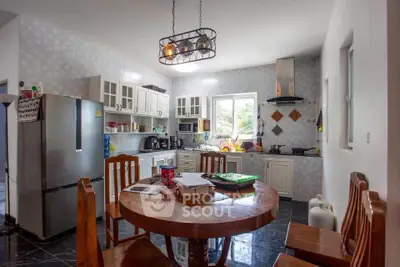 Spacious kitchen with modern appliances and round dining table, perfect for family gatherings.