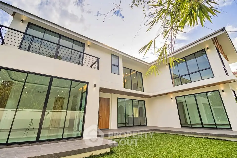 Modern two-story house with large windows and lush green lawn
