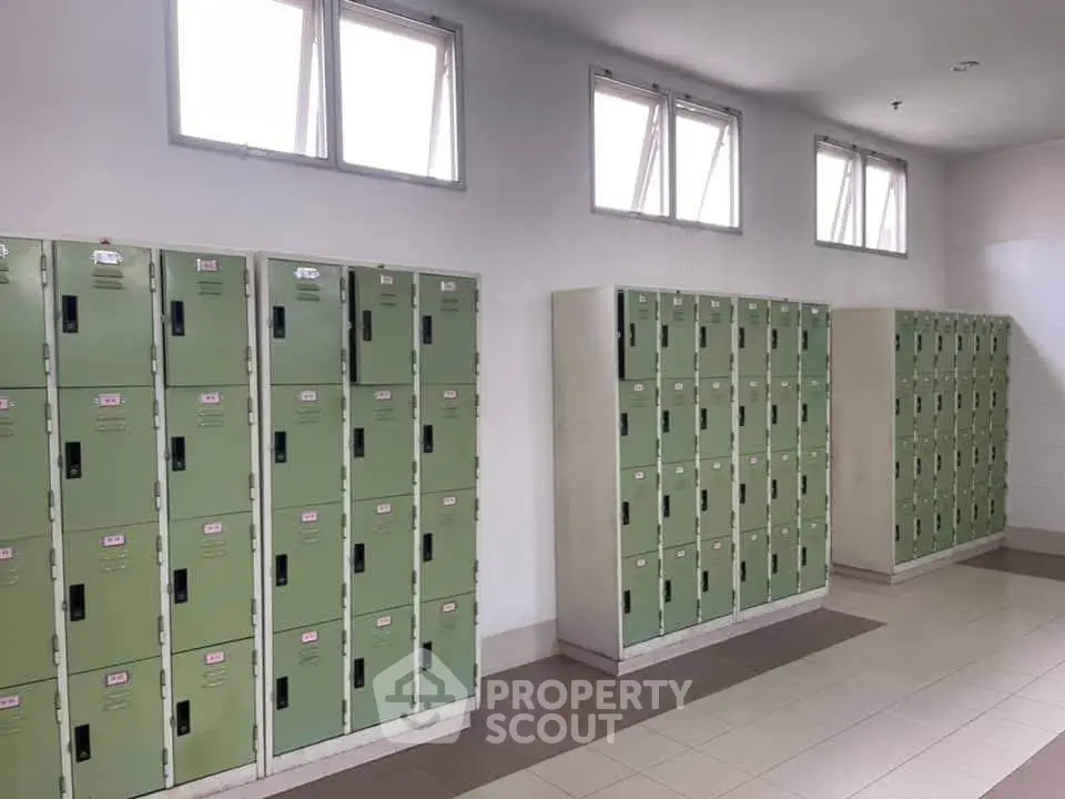 Spacious locker room with multiple green lockers and natural light from windows.