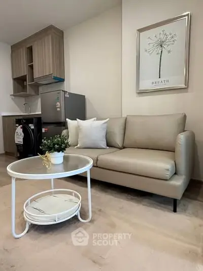 Modern living room with stylish sofa, compact kitchen, and chic decor in a cozy apartment setting.