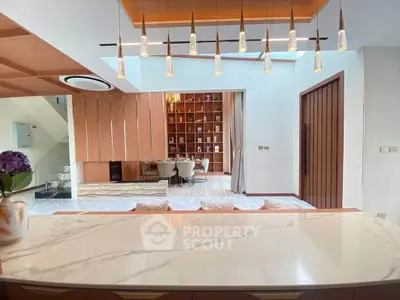 Luxurious open-plan living area with elegant lighting and modern decor, featuring a marble countertop and stylish dining space.