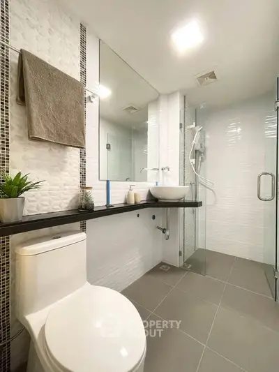 Modern bathroom with sleek design, featuring a glass shower, stylish sink, and elegant tile work.