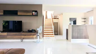 Modern living room with sleek design, featuring a staircase and built-in entertainment unit.