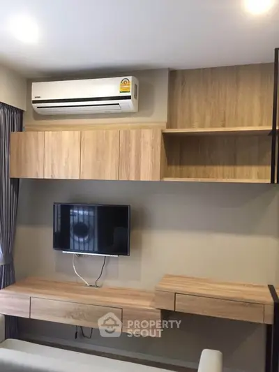 Modern living room with sleek wooden cabinetry and mounted TV, featuring air conditioning for comfort.