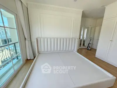 Spacious bedroom with elegant white decor and large window view