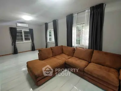 Spacious living room with modern brown sectional sofa and large windows.