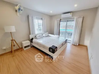 Spacious bedroom with modern furnishings and balcony access, perfect for comfort and relaxation.
