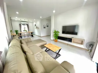 Spacious modern living room with elegant beige sofa and wall-mounted TV, perfect for family gatherings.