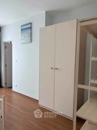 Modern bedroom with wooden flooring and minimalist wardrobe design.