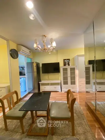 Charming living room with elegant chandelier and modern furnishings, featuring a cozy dining area and sleek appliances.