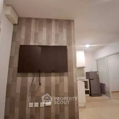 Modern apartment interior with wall-mounted TV and kitchen view