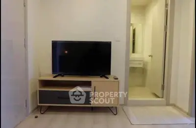 Modern living room with TV stand and adjacent bathroom entrance