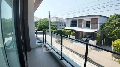 Modern balcony with glass railing overlooking suburban street and houses, perfect for relaxation.