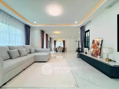 Spacious modern living room with elegant decor and open dining area, featuring a large sectional sofa and stylish lighting.