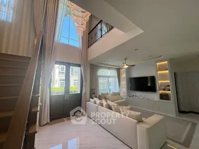 Luxurious living room with high ceilings, elegant chandelier, and modern decor