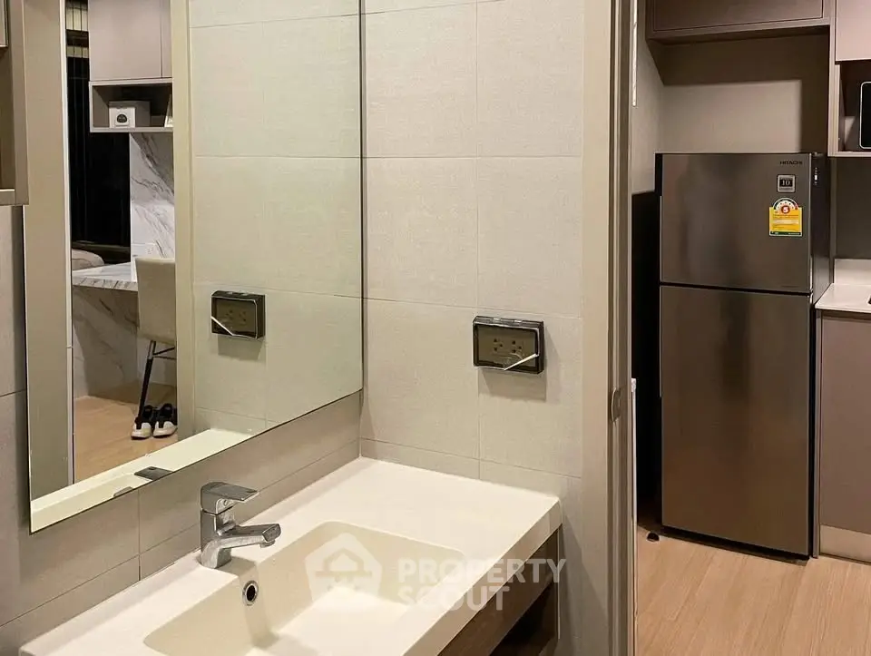 Modern apartment bathroom with sleek fixtures and adjacent kitchen view.