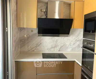 Modern kitchen with sleek cabinetry and built-in appliances, featuring a stylish marble backsplash.