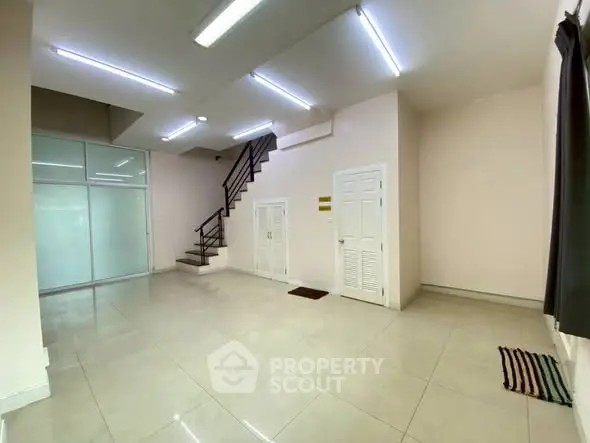 Spacious modern interior with staircase and tiled flooring, ideal for versatile living space.