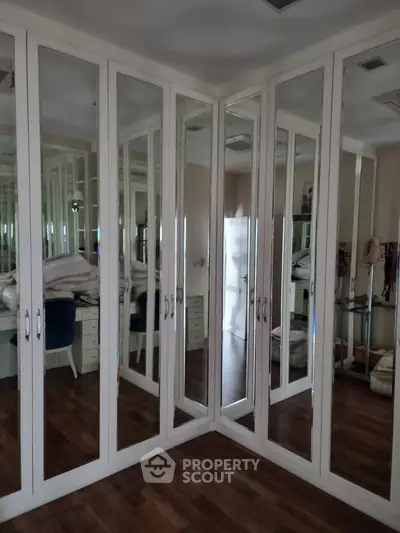 Spacious mirrored corner wardrobe in elegant bedroom setting