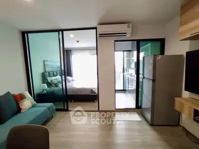 Modern open-plan living room with bedroom view and sleek kitchen appliances.