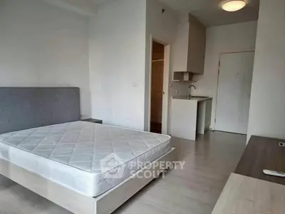 Modern bedroom with minimalist design and compact kitchenette in a bright apartment.