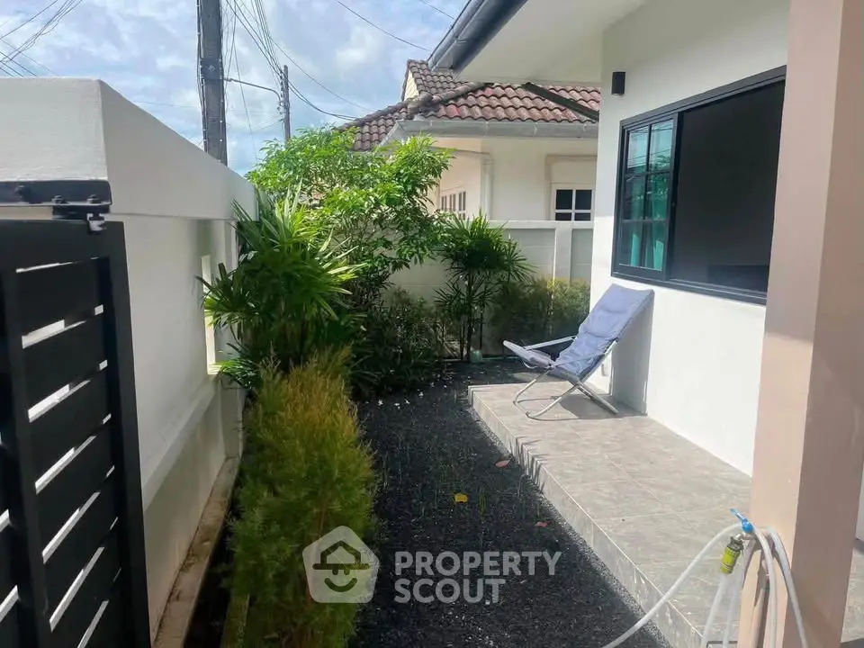 Charming outdoor patio with lush greenery and modern seating, perfect for relaxation in a serene residential setting.