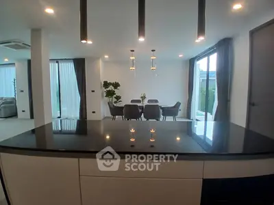 Modern open-plan kitchen and dining area with sleek black countertops and elegant lighting.