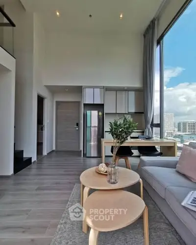Modern living room with high ceilings and large windows offering city views