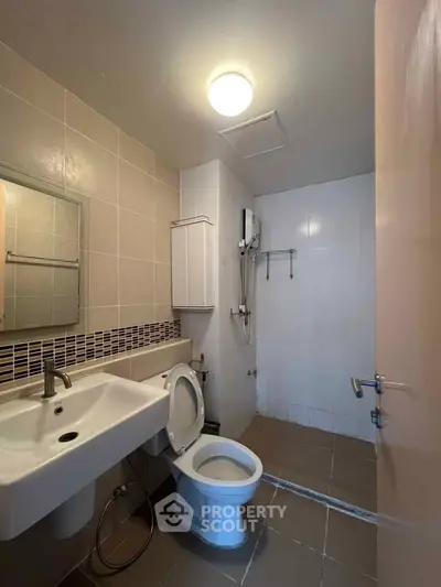 Modern bathroom with sleek fixtures and neutral tiles, featuring a spacious shower area and contemporary design.