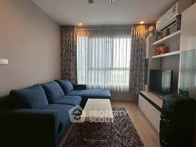 Cozy living room with blue sofa, modern entertainment center, and large window with curtains.