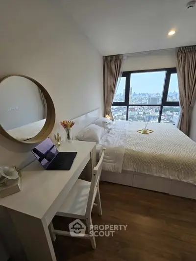 Modern bedroom with city view, featuring a cozy bed, desk, and large window for natural light.