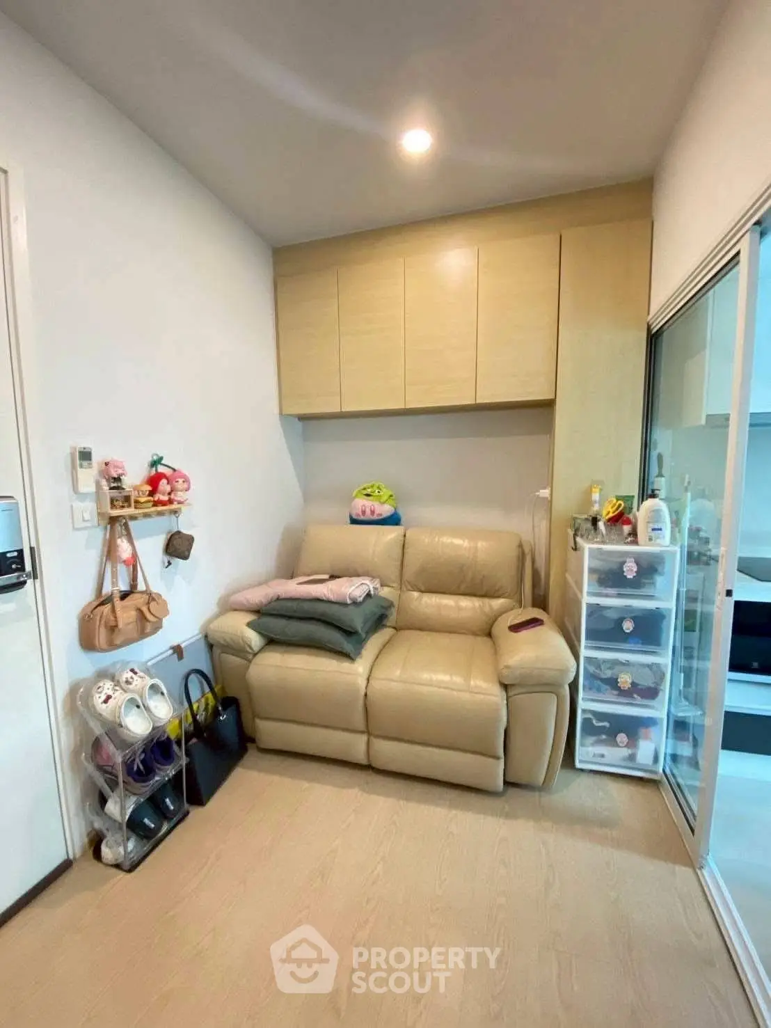 Cozy living room with beige leather sofa and ample storage space, perfect for small apartments.