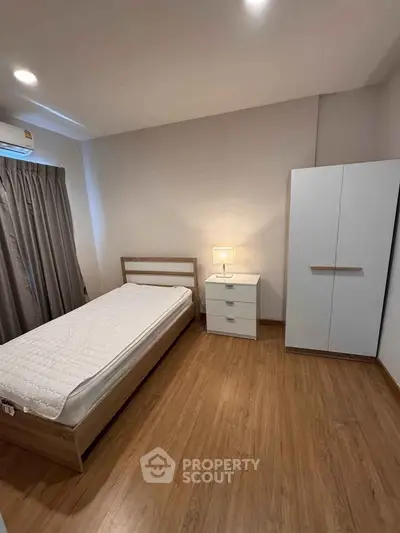 Cozy minimalist bedroom with wooden flooring and modern furniture