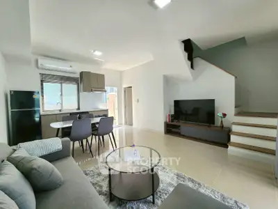 Modern living room with open kitchen and stylish furniture in a bright, airy space.