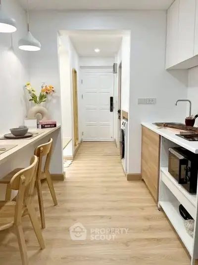 Modern kitchen with wooden flooring and open layout, featuring sleek appliances and stylish lighting.