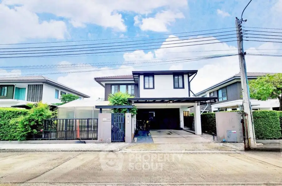 Modern two-story house with driveway and lush greenery in a suburban neighborhood.