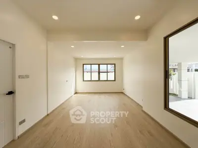 Spacious empty room with large windows and wooden flooring, perfect for customization.