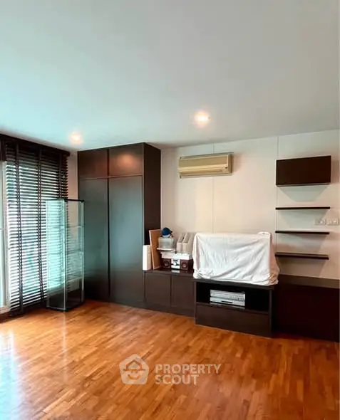 Spacious living room with wooden flooring and modern built-in storage units.