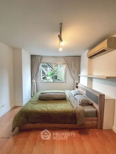 Cozy bedroom with wooden flooring and large window view