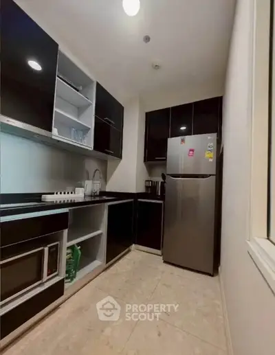 Modern kitchen with sleek black cabinets and stainless steel appliances in a compact layout.