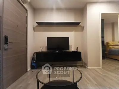 Modern living room with sleek TV stand and glass coffee table, showcasing contemporary interior design.