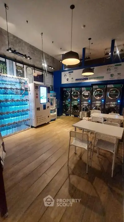 Modern laundry room with vending machines and seating area, featuring sleek design and efficient appliances.