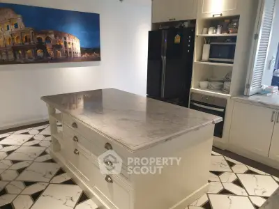 Elegant kitchen with marble island and modern appliances, featuring stylish cabinetry and unique flooring.