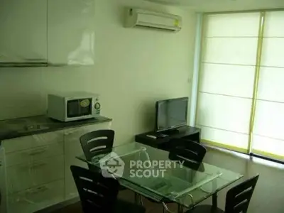 Modern dining area with glass table, TV, and air conditioning in a cozy apartment.