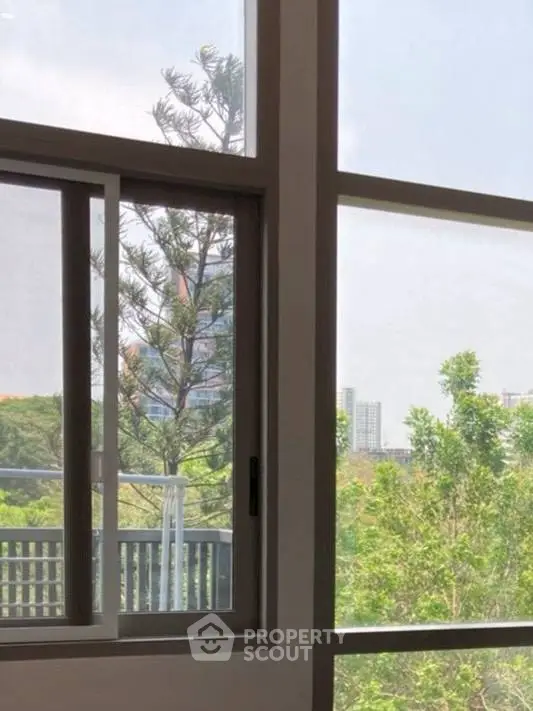 Bright window view with lush greenery and cityscape in the background.