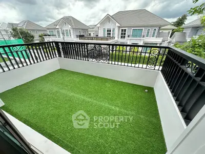 Charming balcony with artificial grass and elegant railing overlooking modern homes.