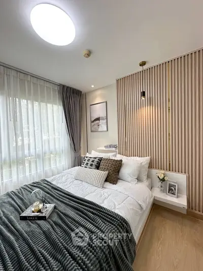 Modern bedroom with stylish decor and natural light, featuring cozy bedding and elegant wall paneling.