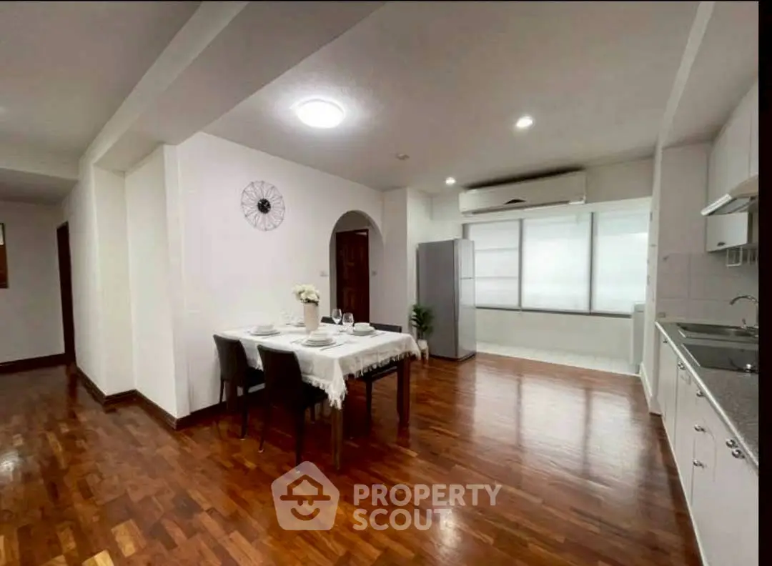 Spacious dining area with wooden flooring and modern kitchen setup.