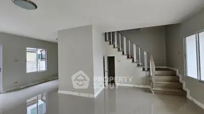 Spacious modern living room with staircase and large windows, perfect for family gatherings.